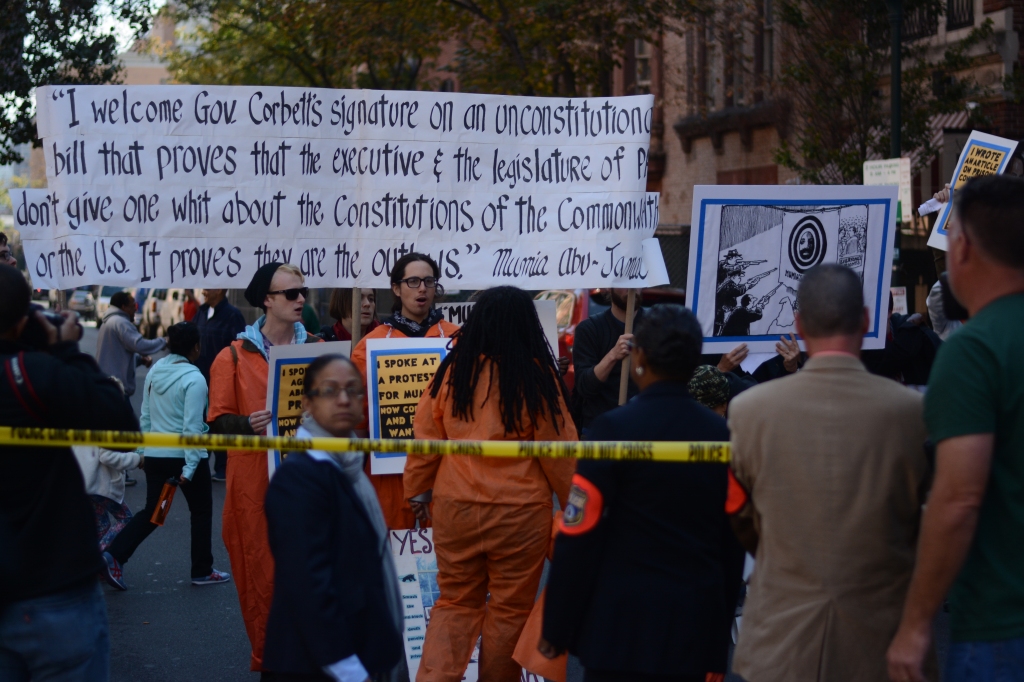 Protesters hold up a banner with Mumia Abu-Jamal's response to the Act's signing. Photo by Joshua Albert